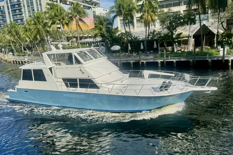 Slide: The Image of 1999 Viking Cockpit Sports Yacht cruising near palm-lined waterfront. - 59