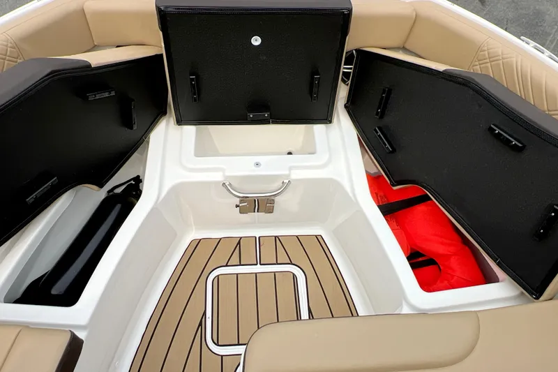 Slide: The Image of 2026 Sea Ray SDX 230 boat storage compartments with tan seating and wood-style flooring. - 9