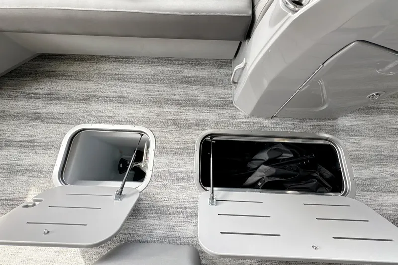 Slide: The Image of 2026 Bennington 24 LSB boat storage compartments with open lids on gray flooring. - 21