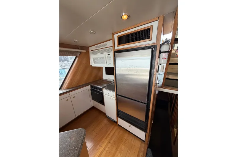 Slide: The Image of 1998 Bayliner 4788 Pilot House Motoryacht kitchen with modern appliances and wood accents. - 16