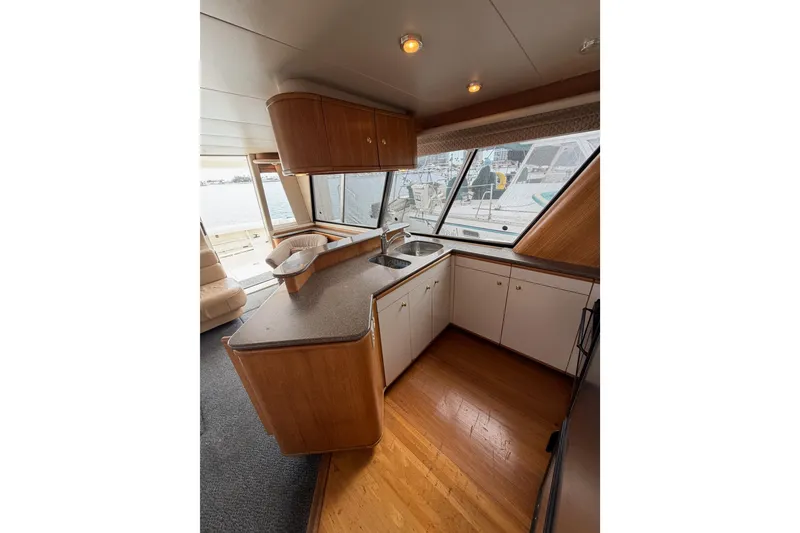 Slide: The Image of 1998 Bayliner 4788 Pilot House Motoryacht kitchen with wood cabinets and large windows. - 17