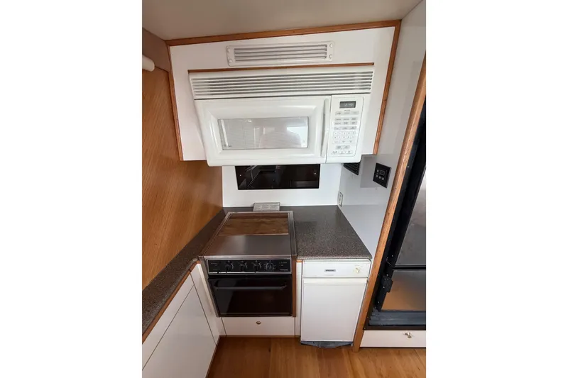 Slide: The Image of 1998 Bayliner 4788 Pilot House Motoryacht kitchen with microwave, oven, and compact design. - 18