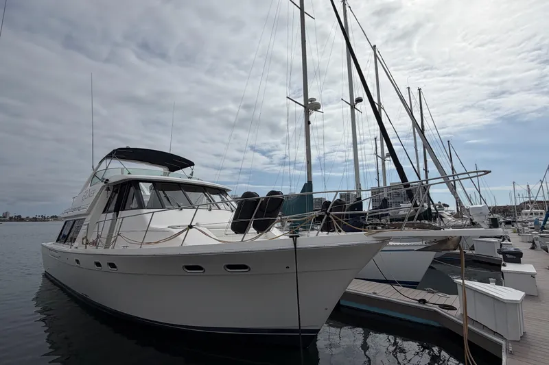 Slide: The Image of 1998 Bayliner 4788 Pilot House Motoryacht docked at marina under cloudy sky. - 2