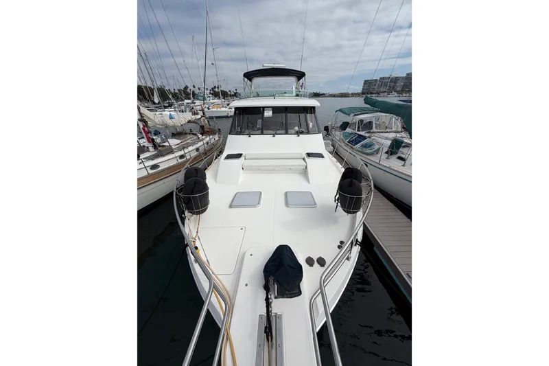 Slide: The Image of 1998 Bayliner 4788 Pilot House Motoryacht docked at marina, surrounded by sailboats. - 36