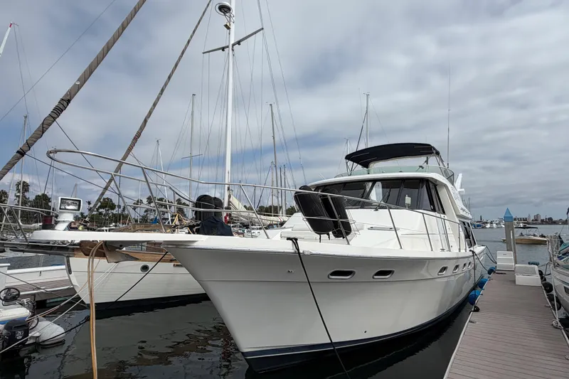 Slide: The Image of 1998 Bayliner 4788 Pilot House Motoryacht docked at marina under cloudy sky. - 4