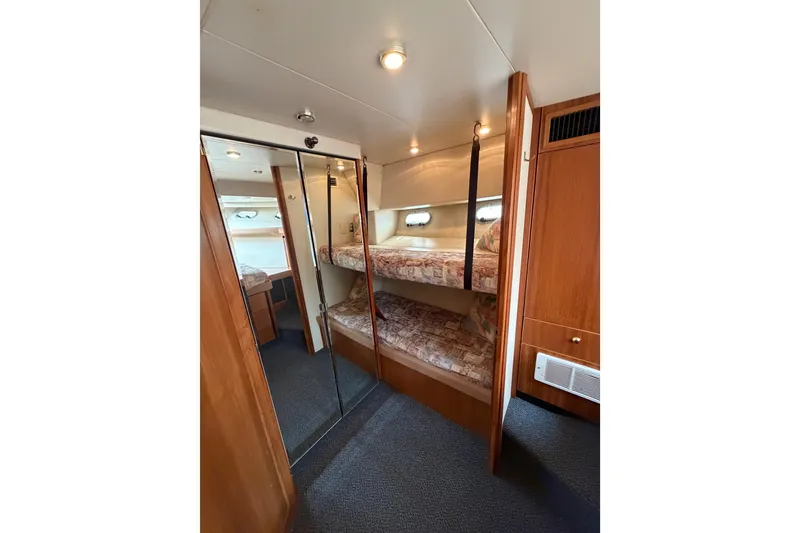 Slide: The Image of 1998 Bayliner 4788 Pilot House Motoryacht cabin with bunk beds and mirrored closet. - 58