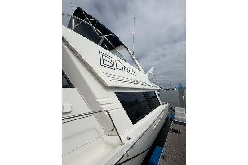 Slide: The Image of 1998 Bayliner 4788 Pilot House Motoryacht docked, showcasing sleek design and branding. - 6