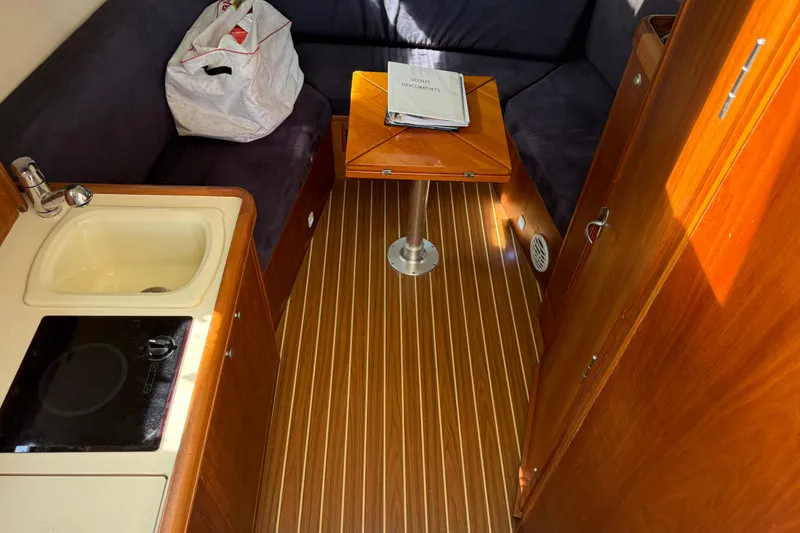 Slide: The Image of 2007 Mainship Pilot 30 Sedan interior with kitchenette, wooden flooring, and seating area. - 11