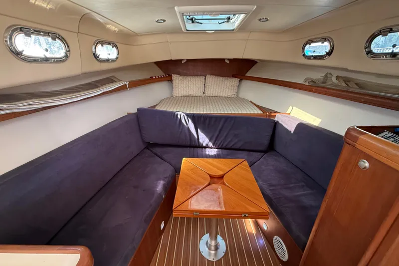 Slide: The Image of 2007 Mainship Pilot 30 Sedan interior with cozy seating and wooden table. - 9