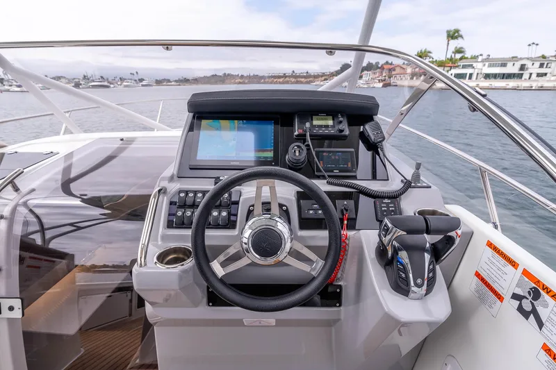 Slide: The Image of 2023 Jeanneau Leader 9.0 WA helm with advanced navigation controls and scenic marina view. - 12