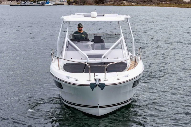 Slide: The Image of 2023 Jeanneau Leader 9.0 WA boat on water, front view, with a person at the helm. - 2