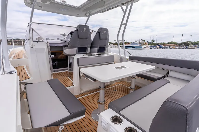Slide: The Image of 2023 Jeanneau Leader 9.0 WA boat interior with seating and table, docked by the water. - 7