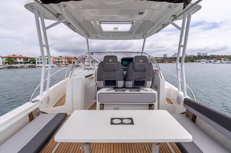 Slide: The Image of 2023 Jeanneau Leader 9.0 WA boat interior with seating and table, docked by waterfront homes. - 8