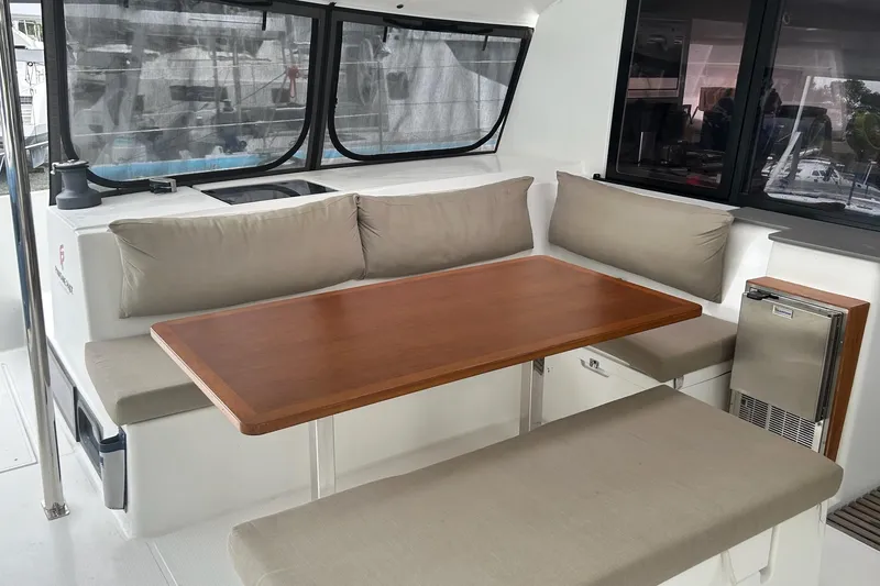 Slide: The Image of 2019 Fountaine Pajot Helia 44 Evolution yacht interior with cushioned seating and wooden table. - 46