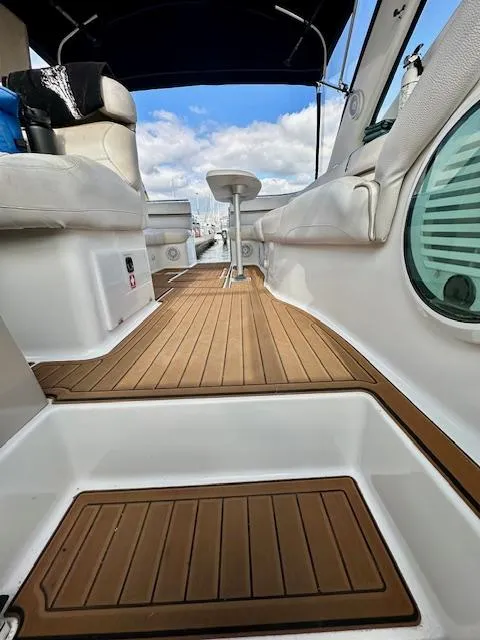 Slide: The Image of 2006 Doral Elegante boat interior with teak flooring and white seating under a blue sky. - 18
