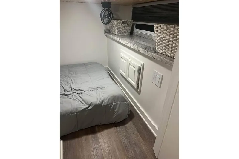 Slide: The Image of 1999 Sharpe houseboat interior with bed, storage baskets, and wood flooring. - 12