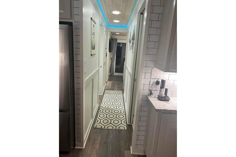 Slide: The Image of Narrow hallway in a 1999 Sharpe houseboat with modern decor and ambient lighting. - 16