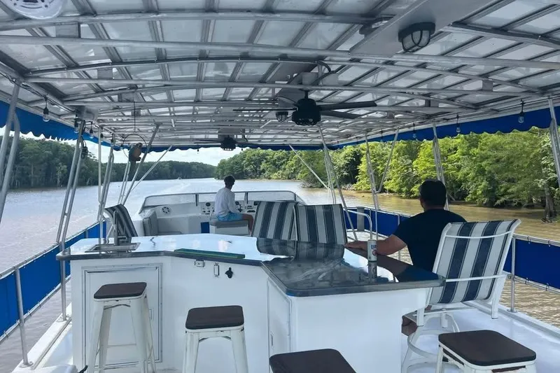 Slide: The Image of 1999 Sharpe houseboat cruising on a river, featuring a spacious deck with seating and canopy. - 3