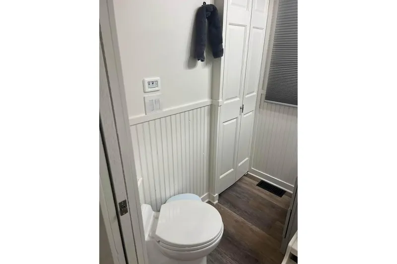 Slide: The Image of Compact bathroom in a 1999 Sharpe houseboat with white paneling and wood flooring. - 9