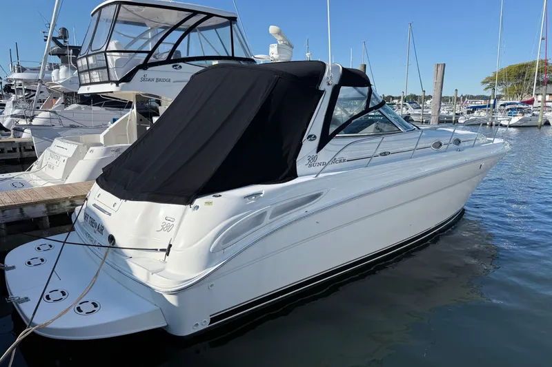Slide: The Image of 2004 Sea Ray 380 Sundancer yacht docked at marina, featuring sleek design and black canopy. - 1