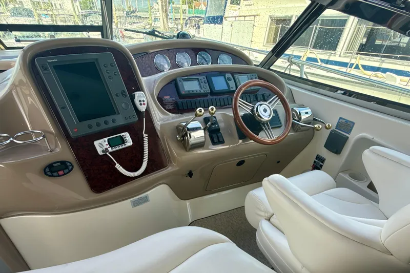 Slide: The Image of 2004 Sea Ray 380 Sundancer helm with steering wheel, navigation controls, and comfortable seating. - 18