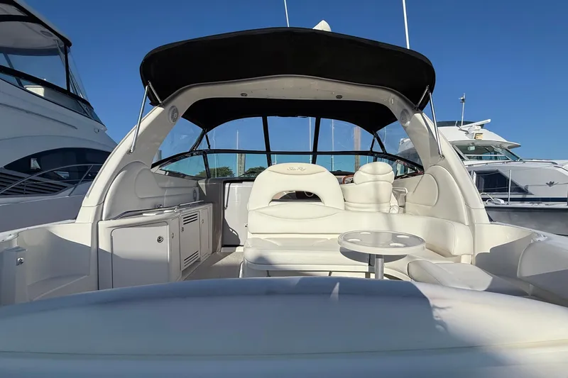 Slide: The Image of 2004 Sea Ray 380 Sundancer yacht interior with white seating and table, docked under clear sky. - 3