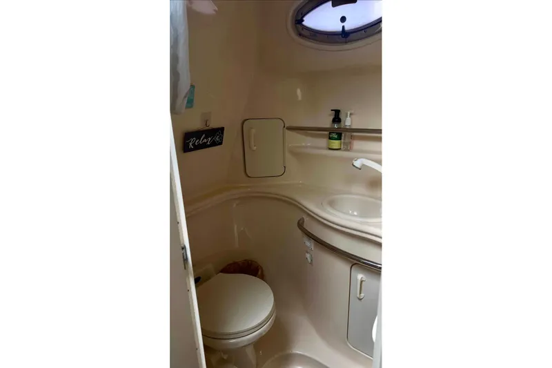 Slide: The Image of 2000 Sea Ray 340 Sundancer bathroom with toilet, sink, and storage shelves. - 10