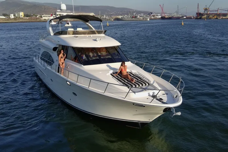 Slide: The Image of 2004 Meridian 580 Pilothouse yacht cruising with passengers in a scenic harbor setting. - 3