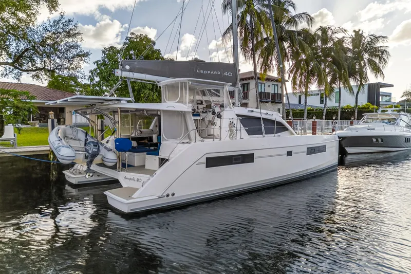 Slide: The Image of 2020 Leopard 40 catamaran docked by palm trees, featuring sleek design and modern amenities. - 2