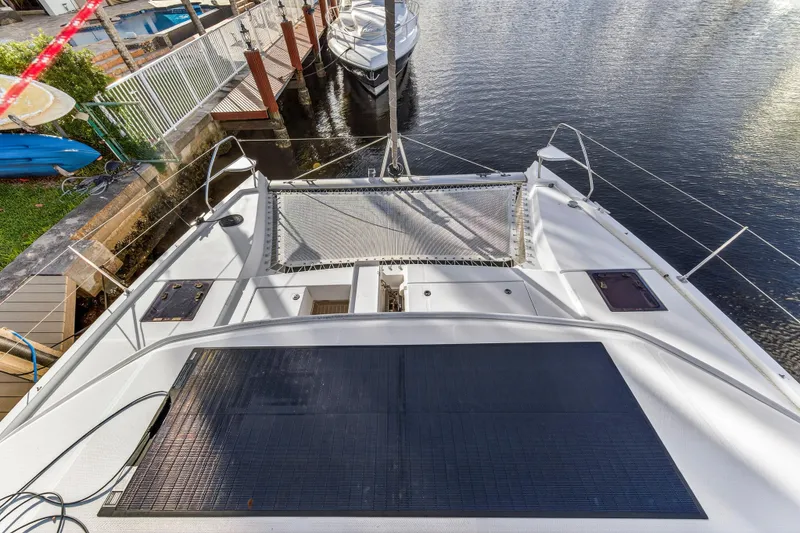 Slide: The Image of 2020 Leopard 40 catamaran docked, featuring spacious deck and netting over water. - 46