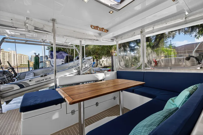Slide: The Image of Interior of 2020 Leopard 40 catamaran with blue seating and wooden table, docked near water. - 56