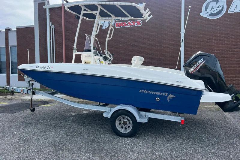 Slide: The Image of 2020 Bayliner Element F18 boat on trailer, blue hull, parked outside a building. - 2