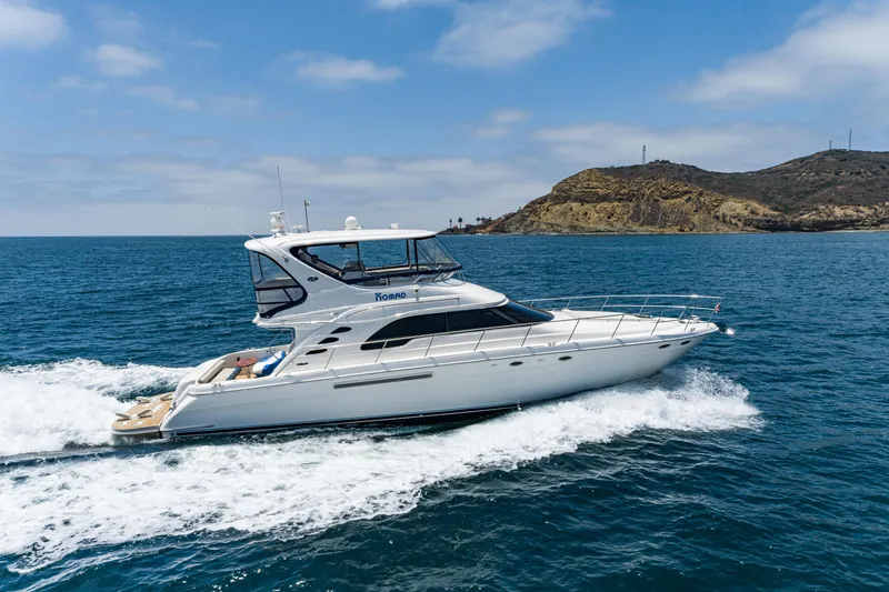 Slide: The Image of 2001 Sea Ray 560 Sedan Bridge yacht cruising on open water near a rocky coastline. - 11