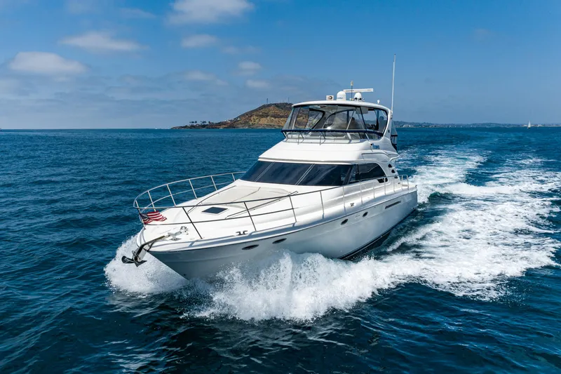 Slide: The Image of 2001 Sea Ray 560 Sedan Bridge yacht cruising on open water, with island in background. - 14