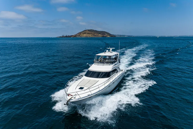 Slide: The Image of 2001 Sea Ray 560 Sedan Bridge yacht cruising on open blue ocean near an island. - 15