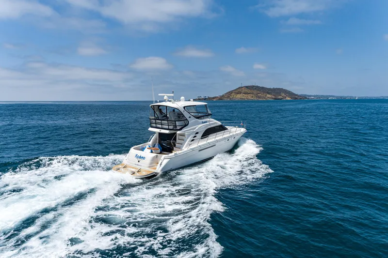 Slide: The Image of 2001 Sea Ray 560 Sedan Bridge yacht cruising on open ocean near an island. - 16