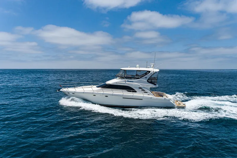 Slide: The Image of 2001 Sea Ray 560 Sedan Bridge yacht cruising on open ocean under blue sky. - 2