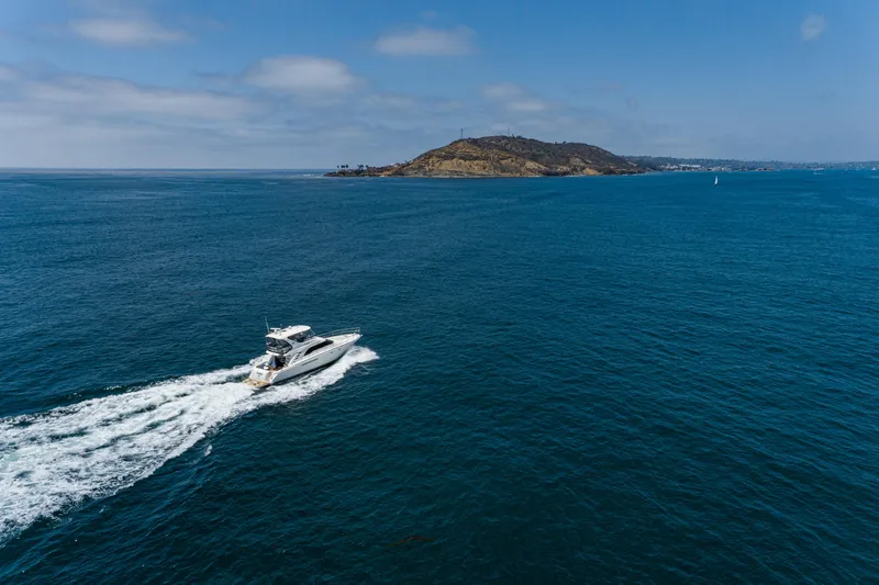 Slide: The Image of 2001 Sea Ray 560 Sedan Bridge yacht cruising on open blue ocean near a distant island. - 26