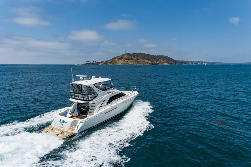 Slide: The Image of 2001 Sea Ray 560 Sedan Bridge yacht cruising on open water near an island. - 3