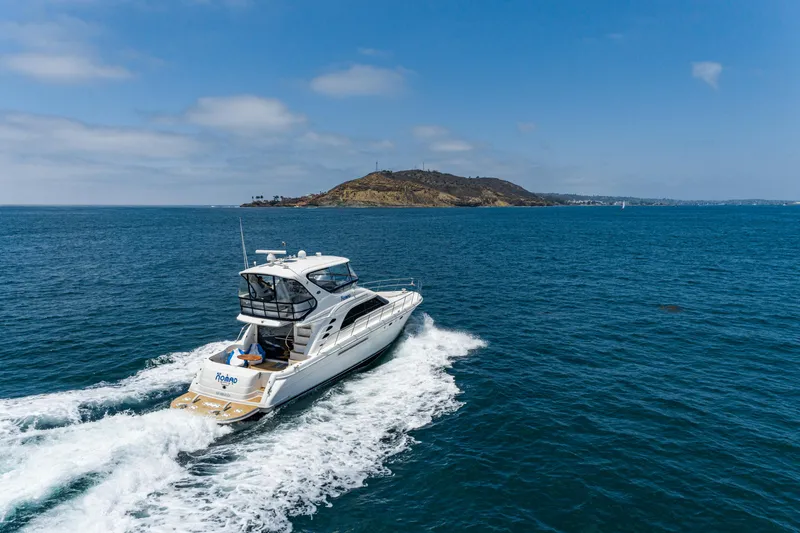 Slide: The Image of 2001 Sea Ray 560 Sedan Bridge cruising on open water near a scenic island. - 5
