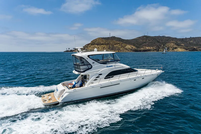 Slide: The Image of 2001 Sea Ray 560 Sedan Bridge yacht cruising on blue ocean near rocky coastline. - 6