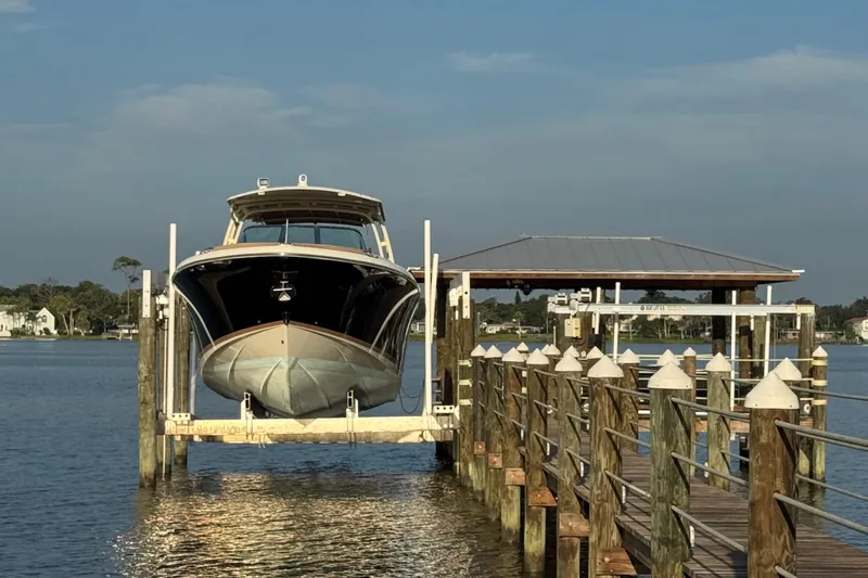 Slide: The Image of 2016 Chris-Craft Launch 36 boat docked on a lift by a wooden pier. - 33