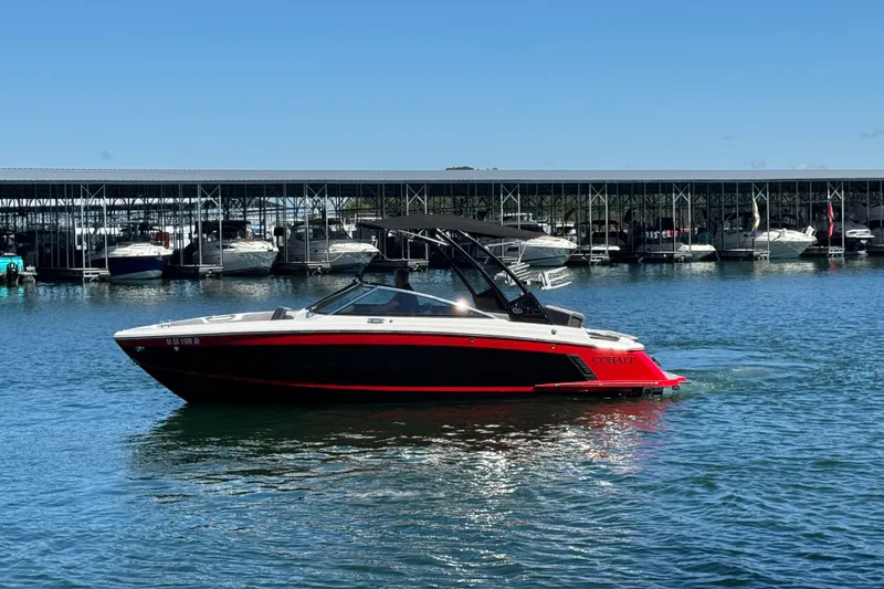 Slide: The Image of 2023 Cobalt R4 Surf boat on water near marina, clear blue sky. - 10