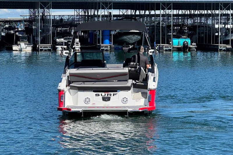 Slide: The Image of 2023 Cobalt R4 Surf boat cruising in marina, rear view with docked boats. - 3