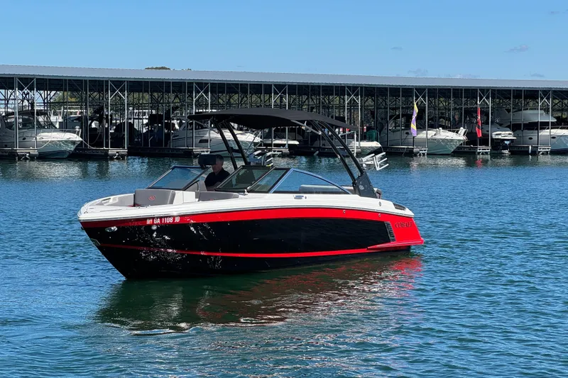 Slide: The Image of 2023 Cobalt R4 Surf boat on water near marina, featuring sleek red and black design. - 5