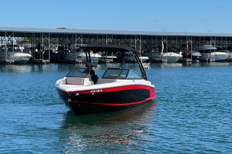 Slide: The Image of 2023 Cobalt R4 Surf boat on water near marina, under clear blue sky. - 6