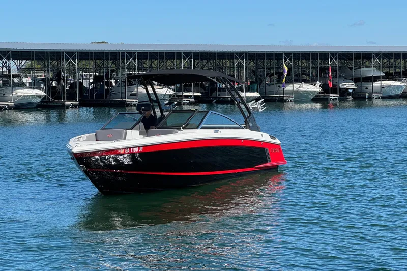 Slide: The Image of 2023 Cobalt R4 Surf boat on water near marina, featuring sleek black and red design. - 7