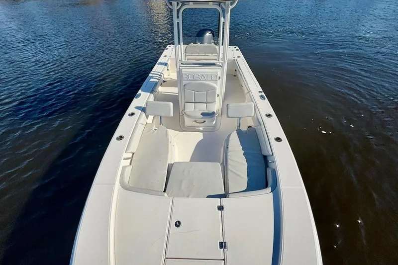 Slide: The Image of 2017 Robalo 246 Cayman boat on calm water, showcasing spacious deck and seating. - 11