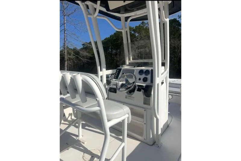 Slide: The Image of 2017 Robalo 246 Cayman boat console with steering wheel and gauges, set against a wooded backdrop. - 5