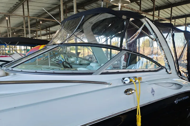 Slide: The Image of 2004 Crownline 270 CR boat docked under a metal roof, featuring a sleek design and clear canopy. - 22